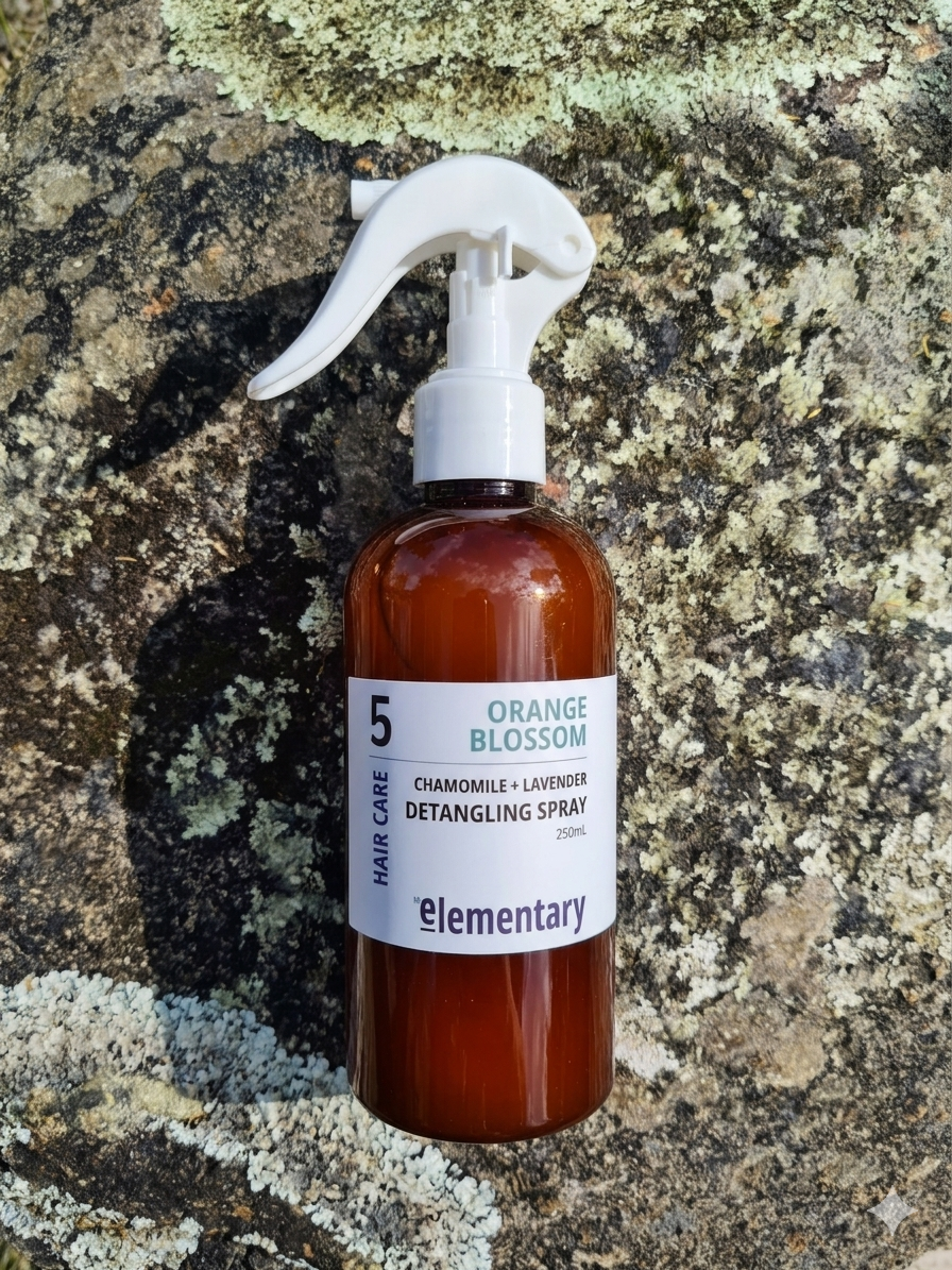Detangling spray bottle labeled 'Elementary' on a textured stone background