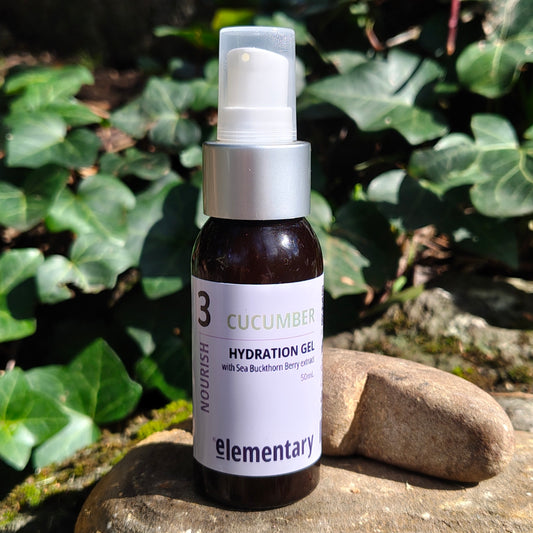 A 50ml bottle of Elementary Cucumber Hydration Gel, resting on a stone with a background of green ivy leaves.