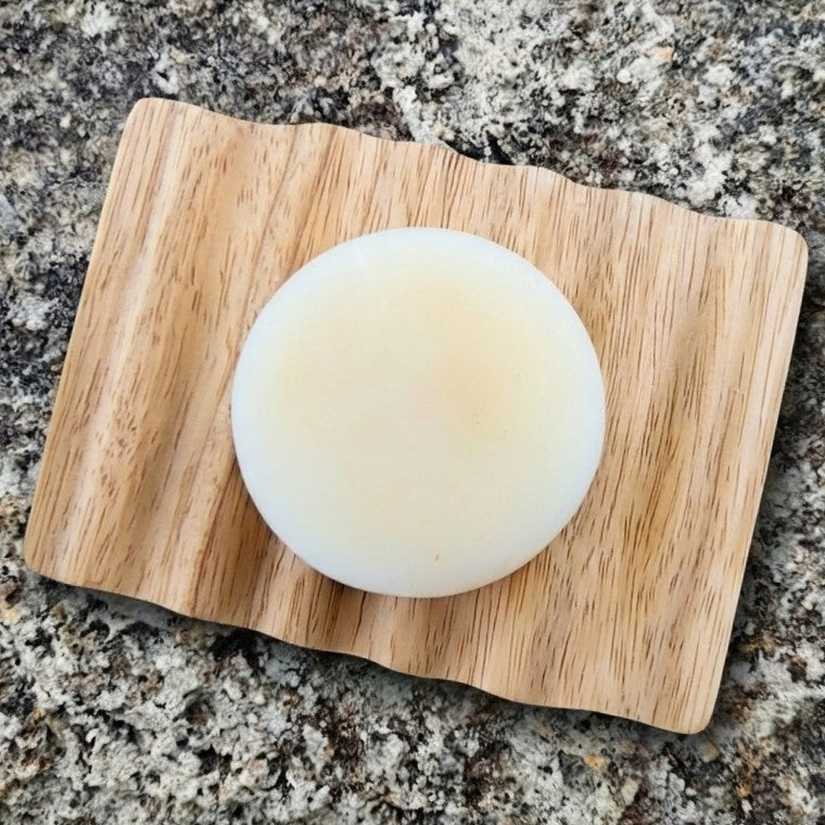 Elementary solid conditioner bar on a bamboo soap dish on a granite surface