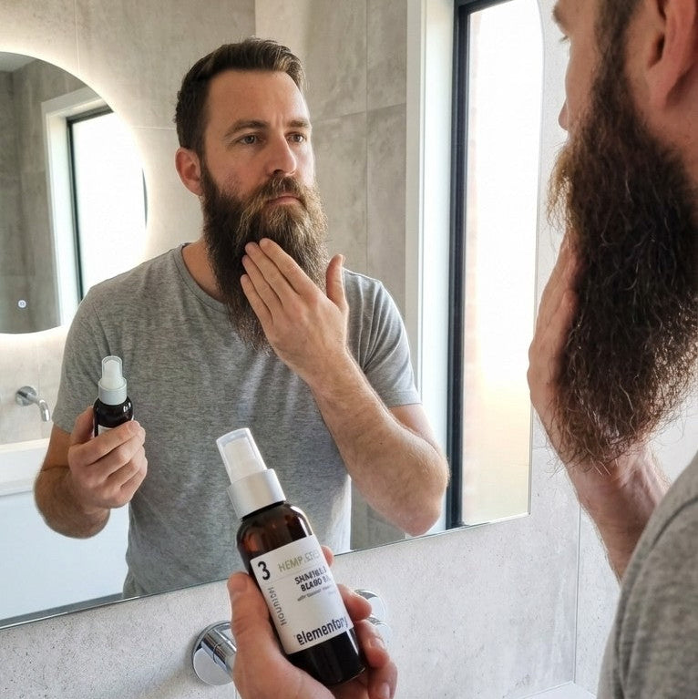 Man applying a beard oil product in front of a mirror